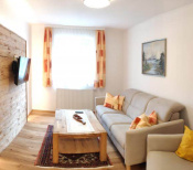 Gemütliches Wohnzimmer der Ferienwohnung mit Sofa, Holztisch und Fernseher in Mühlbach am Hochkönig.